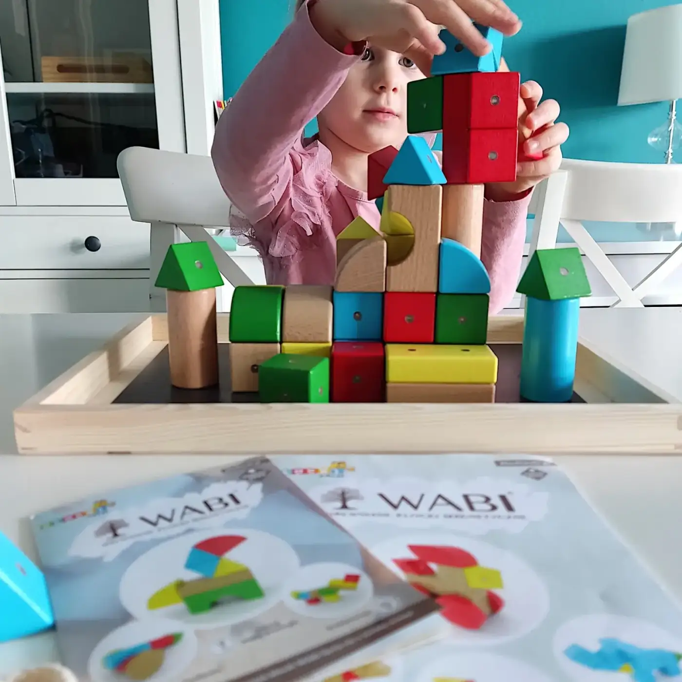 Dziecko konstruujące zamek z drewnianych klocków WABI